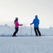Two skiers enjoying the snowy slopes of Crans-Montana, Switzerland, with panoramic views of the Swiss Alps.